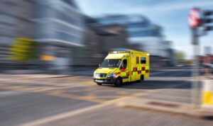 A yellow ambulance rushing through a city to an emergency.