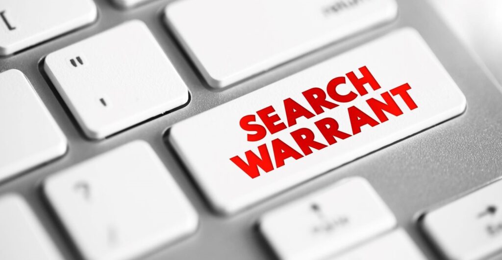 A keyboard with the words "search warrant" on the Shift Key