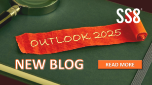 A desk with a magnifying glass and a paper that says "Outlook 2025", and text "SS8, New Blog, and Read More"