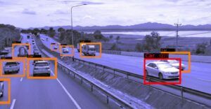 Une autoroute avec de la circulation et plusieurs voitures mises en évidence par des rectangles orange, ainsi qu'une voiture mise en évidence par un rectangle rouge.