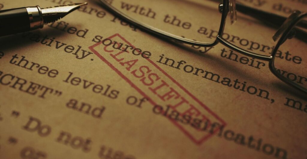 A closeup view of a document with a red CLASSIFIED stamp across it.